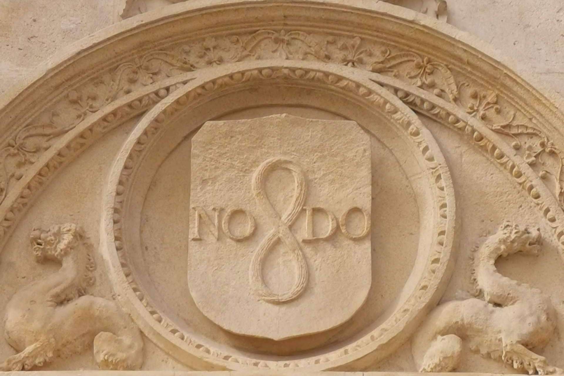 ¿Qué simboliza la inscripción ubicada en diferentes lugares de Sevilla, NO8DO?